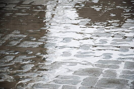 Pfützen und Straßenlichter im Regen
