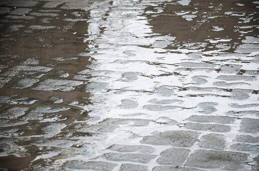 Pfützen und Straßenlichter im Regen